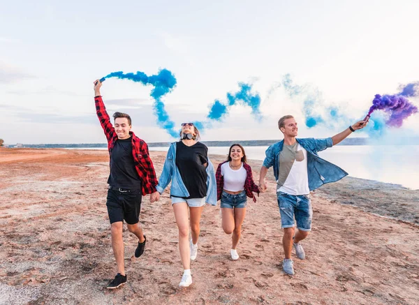 Jovens amigos correndo com flare mão ou fusee — Fotografia de Stock