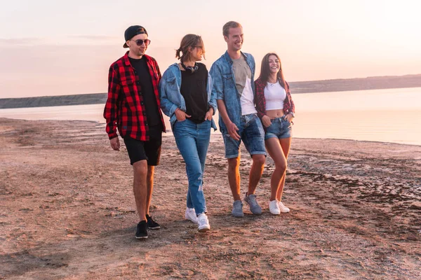 Amigos en la playa juntos caminando al atardecer — Foto de Stock