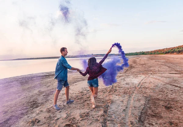 Joven pareja corriendo con mano bengala o fusee — Foto de Stock