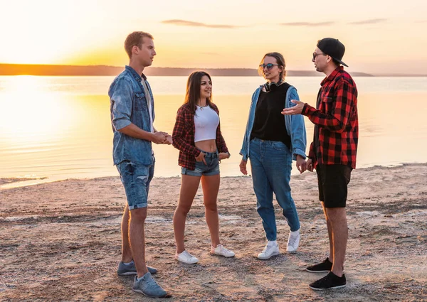 Pareja de amigos en la playa juntos caminando durante la puesta del sol — Foto de Stock