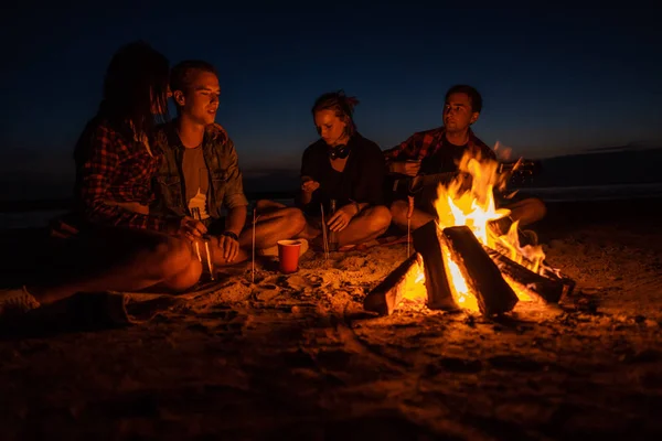 Jóvenes amigos tienen picnic con hoguera en la playa — Foto de Stock