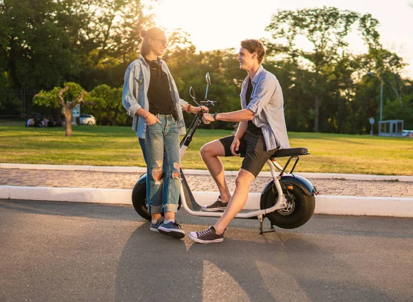 Preciosa joven feliz pareja con bicicleta eléctrica — Foto de Stock