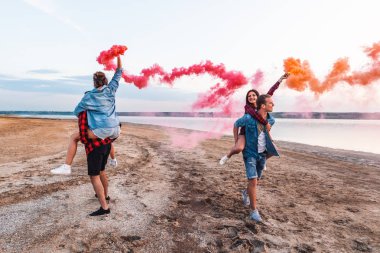 Grup Genç arkadaşlar kumsal boyunca çalışan ve el parlama veya fusee tutarak. Özgürlük ve bağımsızlık kavramı