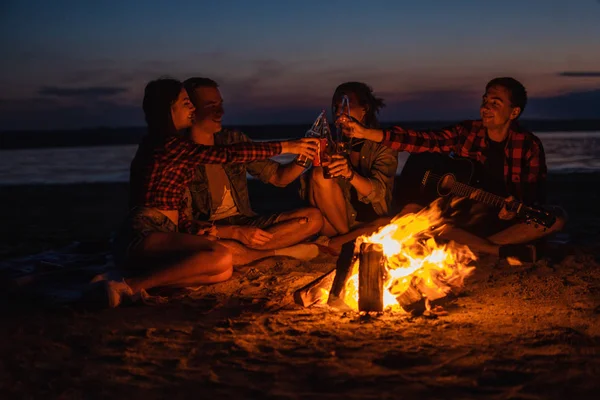 young friends have picnic with bonfire on the beach