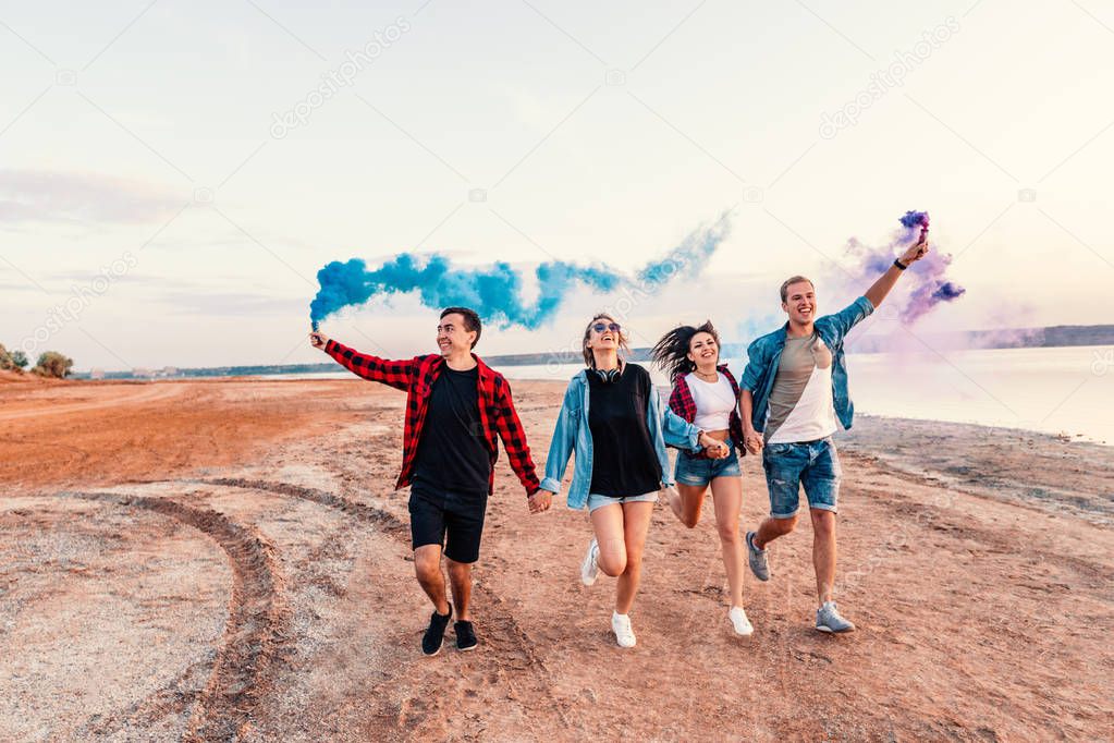 young friends running with hand flare or fusee