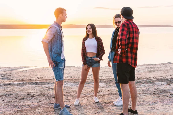 Par vänner på stranden tillsammans promenader under solnedgången — Stockfoto