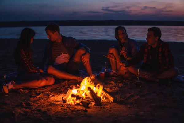 Jóvenes amigos tienen picnic con hoguera en la playa — Foto de Stock