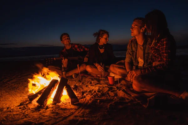 Jóvenes amigos tienen picnic con hoguera en la playa —  Fotos de Stock