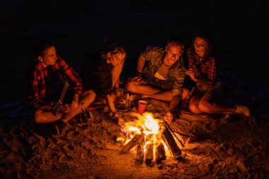 Genç çiftler şenlik ateşi ile Sahilde piknik