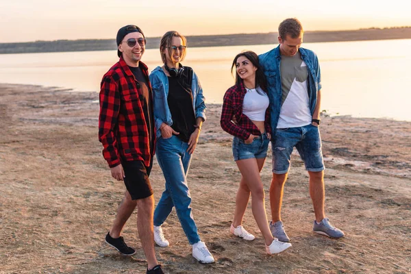 Amigos en la playa juntos caminando al atardecer — Foto de Stock