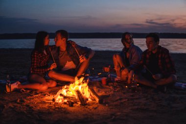 Sahilde piknik şenlik ateşi ile genç arkadaşlar