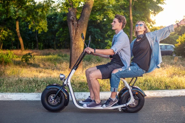 Preciosa pareja joven conduciendo bicicleta eléctrica durante el verano —  Fotos de Stock