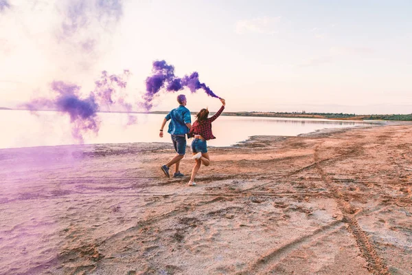 Joven pareja corriendo con mano bengala o fusee — Foto de Stock