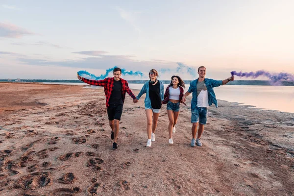 Jóvenes amigos corriendo con bengalas o fusee — Foto de Stock