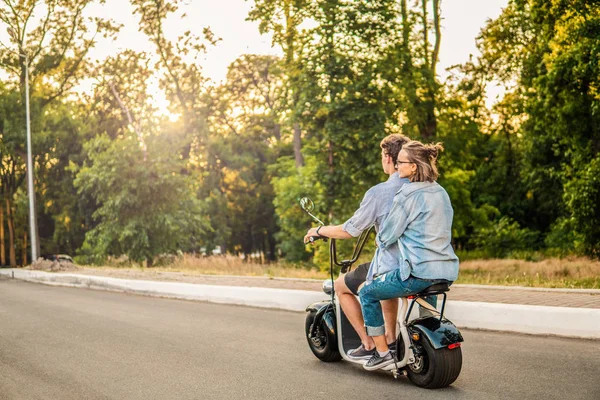 Прекрасная молодая пара за рулем электрического велосипеда летом — стоковое фото