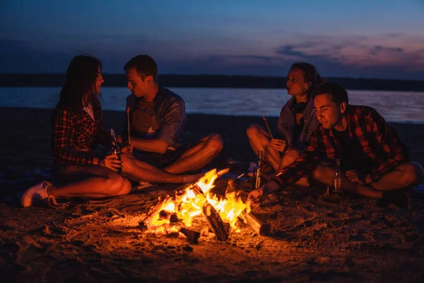 Teman-teman muda telah piknik dengan api unggun di pantai — Stok Foto