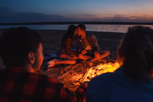 Jóvenes amigos tienen picnic con hoguera en la playa — Foto de Stock