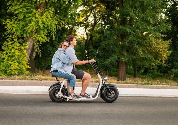 Preciosa pareja joven conduciendo bicicleta eléctrica durante el verano — Foto de Stock