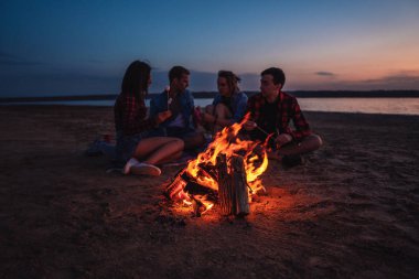 Sahilde piknik şenlik ateşi ile genç arkadaşlar