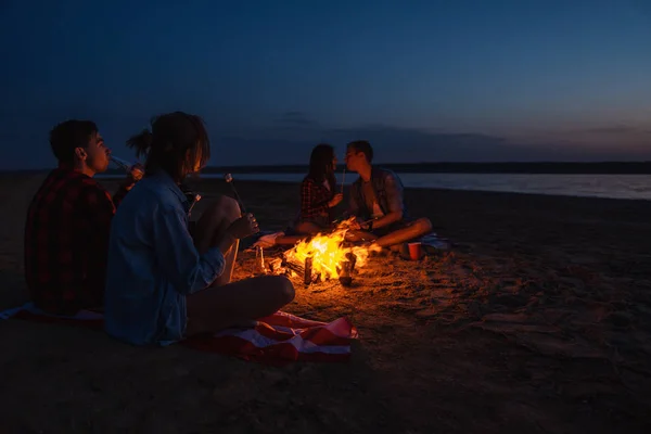 Jóvenes amigos tienen picnic con hoguera en la playa — Foto de Stock