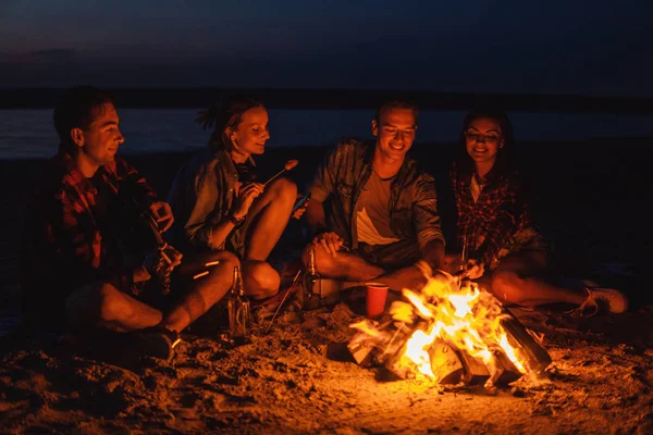 Jóvenes amigos tienen picnic con hoguera en la playa —  Fotos de Stock