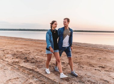 oung çift sahilde birlikte yürüme