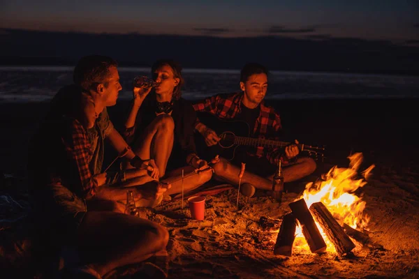 Jóvenes amigos tienen picnic con hoguera en la playa — Foto de Stock