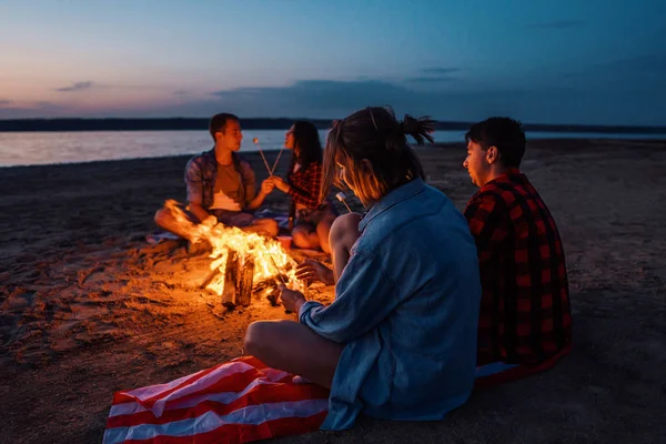 Jóvenes amigos tienen picnic con hoguera en la playa — Foto de Stock