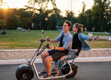 Güzel genç çift elektrikli bisiklet yaz boyunca sürüş. Modern şehir uzanan ve ulaşım