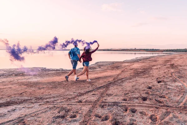 Joven pareja corriendo con mano bengala o fusee — Foto de Stock