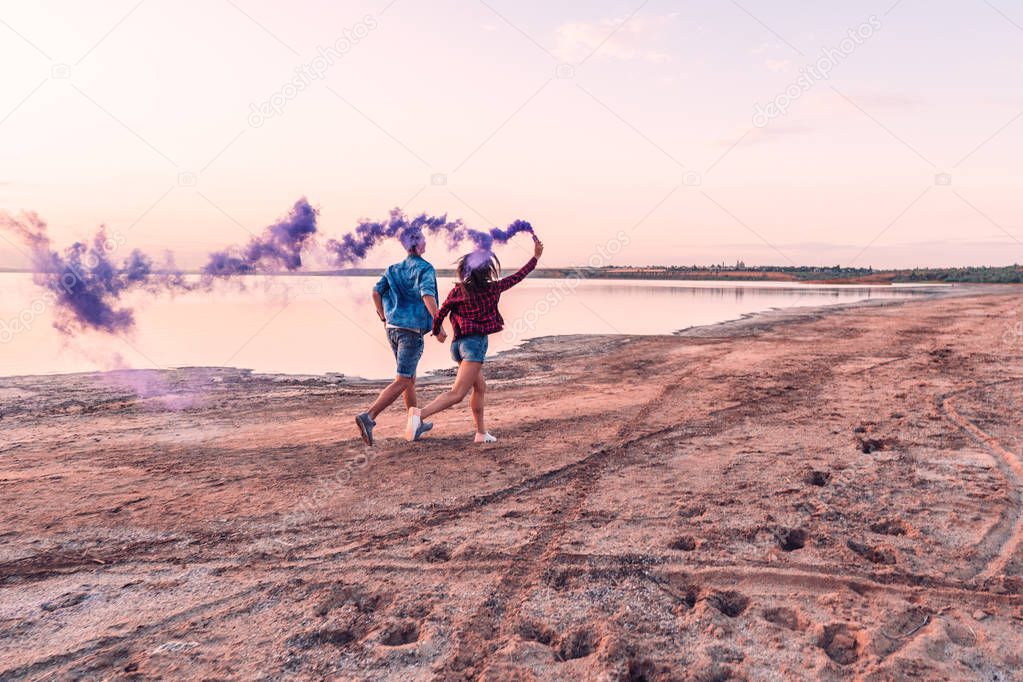 young couple running with hand flare or fusee