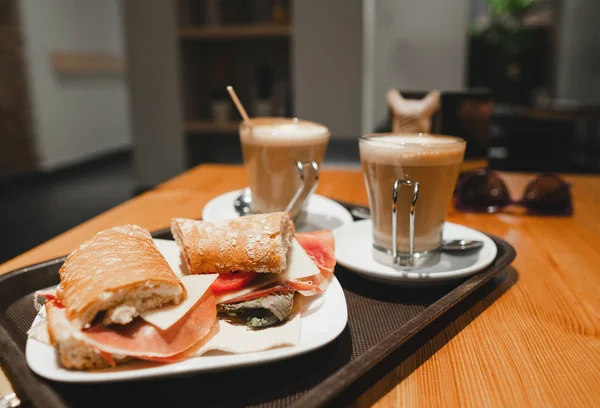 Mic dejun gustare - cafea latte și sandwich bocadillo pe masă într-o cafenea — Fotografie, imagine de stoc