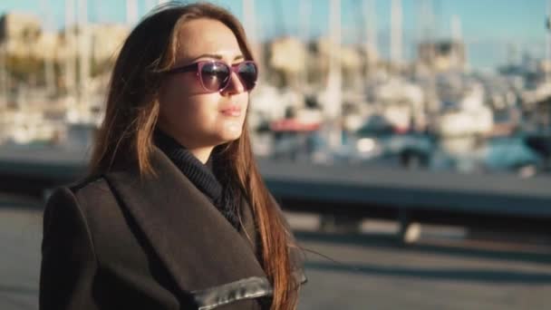 Mujer en gafas de sol caminando con una gran cantidad de yates y barcos detrás — Vídeos de Stock