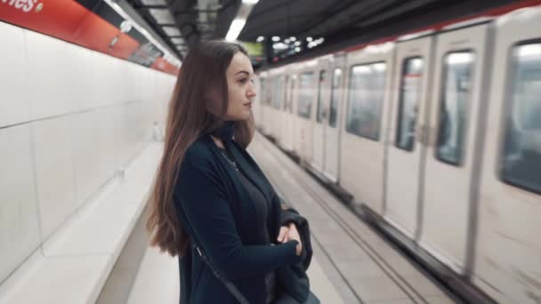 Chica joven de pie en el andén y esperando el tren para llegar — Vídeo de stock