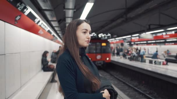 Gadis muda berdiri di peron dan menunggu kereta datang — Stok Video