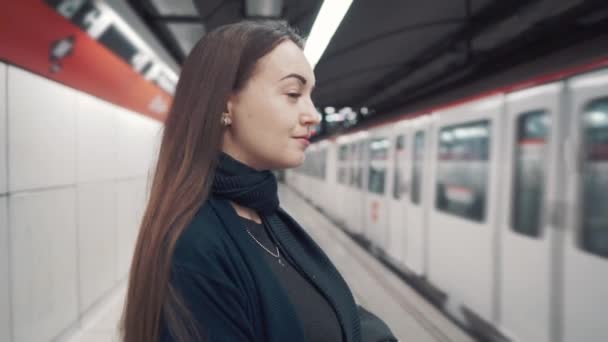 Девушка, стоящая на платформе и ожидающая прибытия поезда — стоковое видео