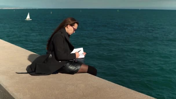 Mulher desenhando esboços em seu caderno de esboços ao ar livre perto do mar. tiro em câmara lenta — Vídeo de Stock