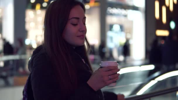 Slowmotion πλάνο του μια κοπέλα που γουλιές καφέ στην πόλη το βράδυ — Αρχείο Βίντεο