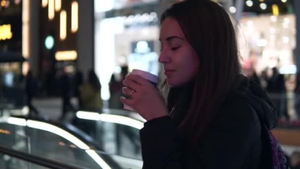 Toma de cámara lenta de una chica que bebe café en la ciudad nocturna — Vídeos de Stock