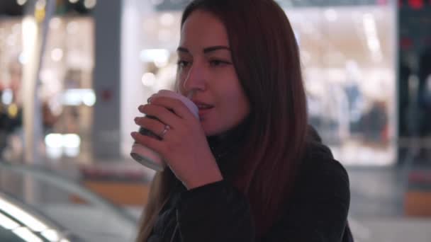 Tikje schot van een meisje dat SIP's koffie in de stad van de nacht — Stockvideo