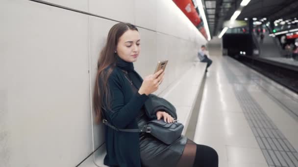 Frau tippt in U-Bahn-Station auf Smartphone. Warten auf Zug — Stockvideo