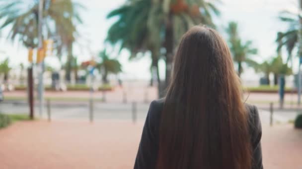 Attraktive junge Touristin wedelt in der Nähe des Palmbuschs — Stockvideo