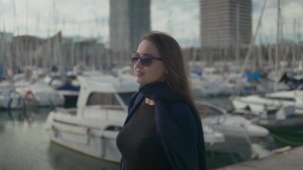 Mujer en gafas de sol caminando con una gran cantidad de yates y barcos detrás — Vídeo de stock