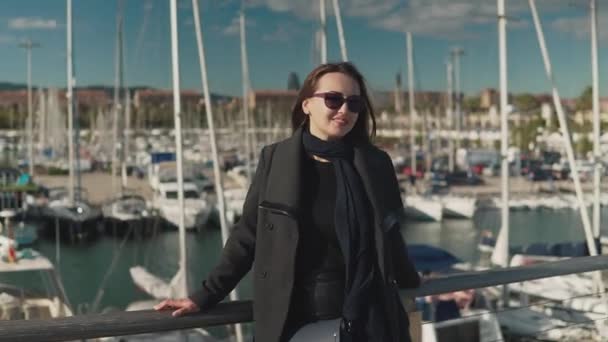 Kvinna i solglasögon promenader med en massa yachter och båtar bakom — Stockvideo