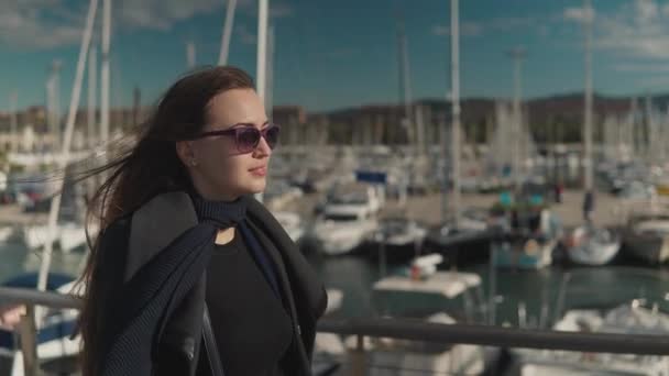 Mujer en gafas de sol caminando con una gran cantidad de yates y barcos detrás — Vídeos de Stock