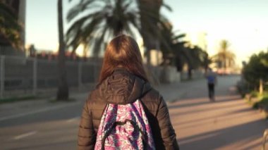 Sırtında bir sırt çantası ile kız turistik palm mesire yürür