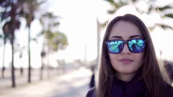 Девушка улыбается в солнечных очках с ладонями на заднем плане — стоковое видео