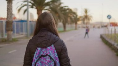 Sırtında bir sırt çantası ile kız turistik palm mesire yürür