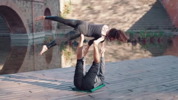 Hermosa pareja practicando acro yoga por la mañana — Vídeo de stock