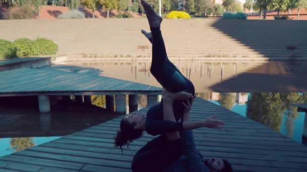 Прекрасная пара практикующая акро-йогу по утрам — стоковое видео